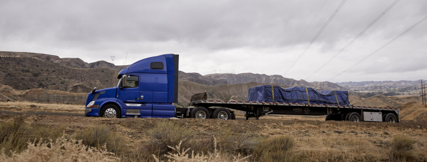 Blue flatbed truck in mountainous terrain